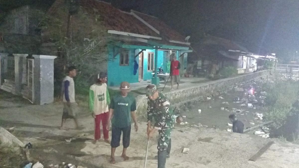 Babinsa dan Warga Bersih-Bersih Irigasi di Malam Hari